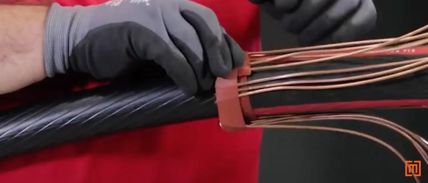 Technician covers bent concentric wires with a layer of mastic tape