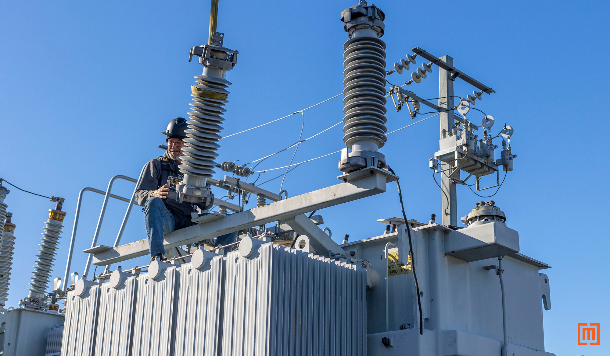 Technician working on substation with large bushings