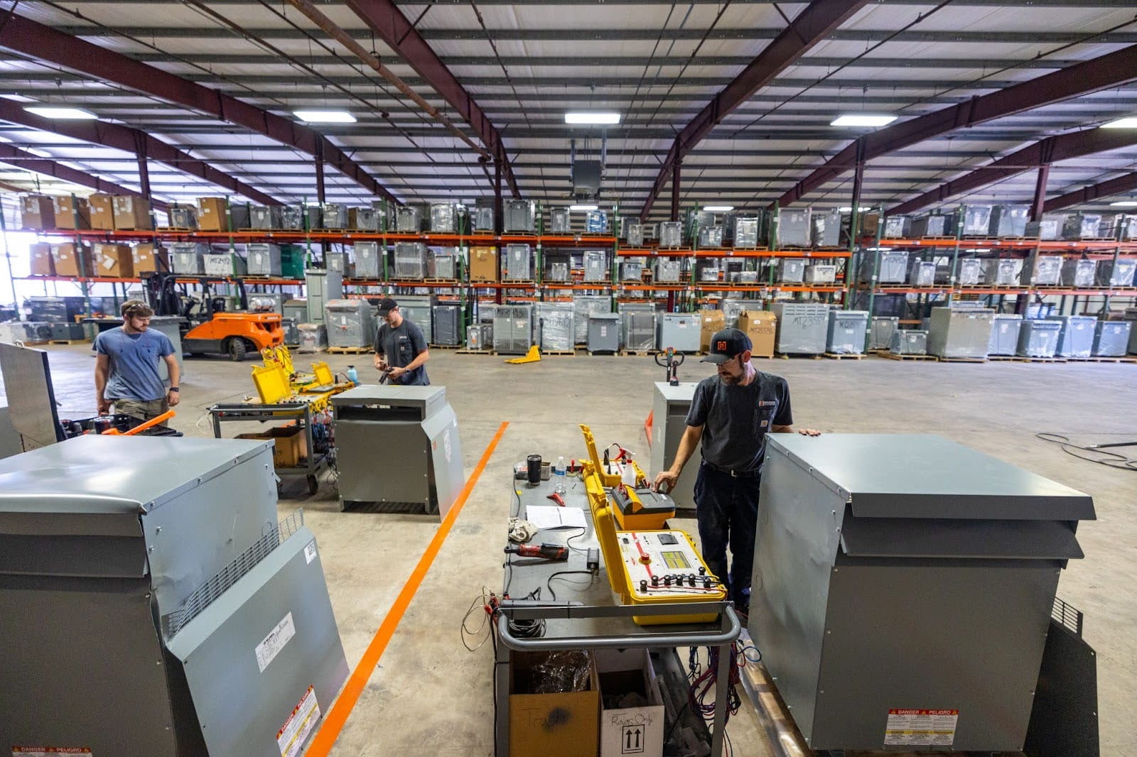 photo of transformer techs working in a warehouse with lots of transformers on shelves