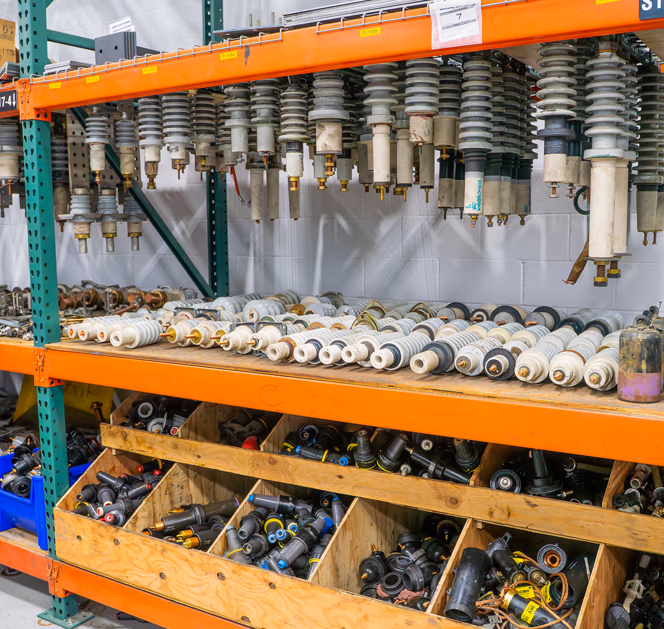 Shelves storing various cylindrical and insulator parts organized in a warehouse or workshop.