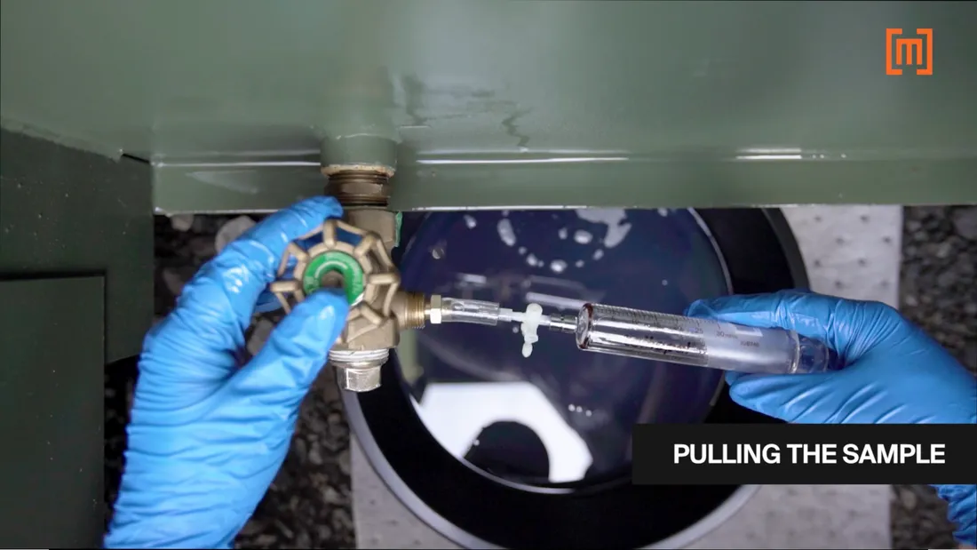 A technician pulling a DGA oil sample from a padmount transformer