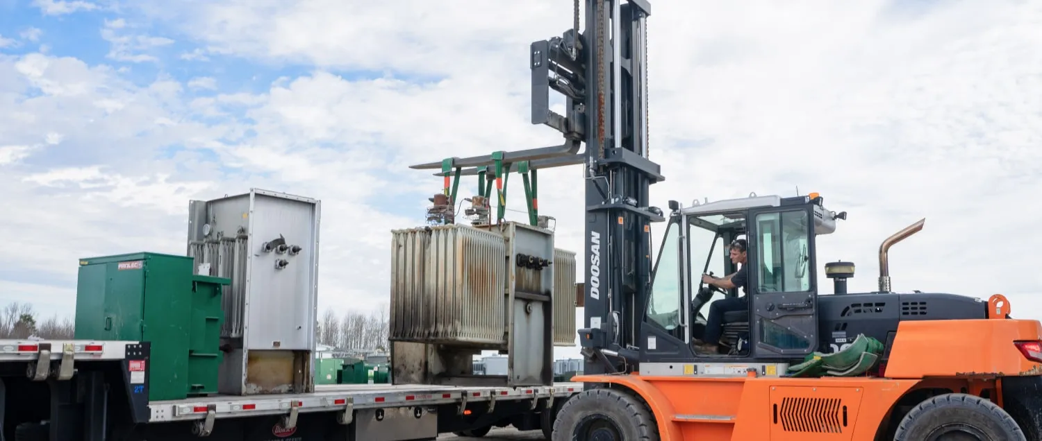Forklift loading substation transformer onto truck