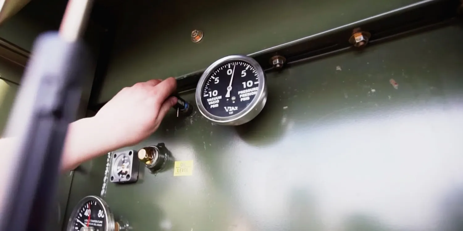 Hand pulling pressure release valve next to a pressure gauge on a padmount transformer